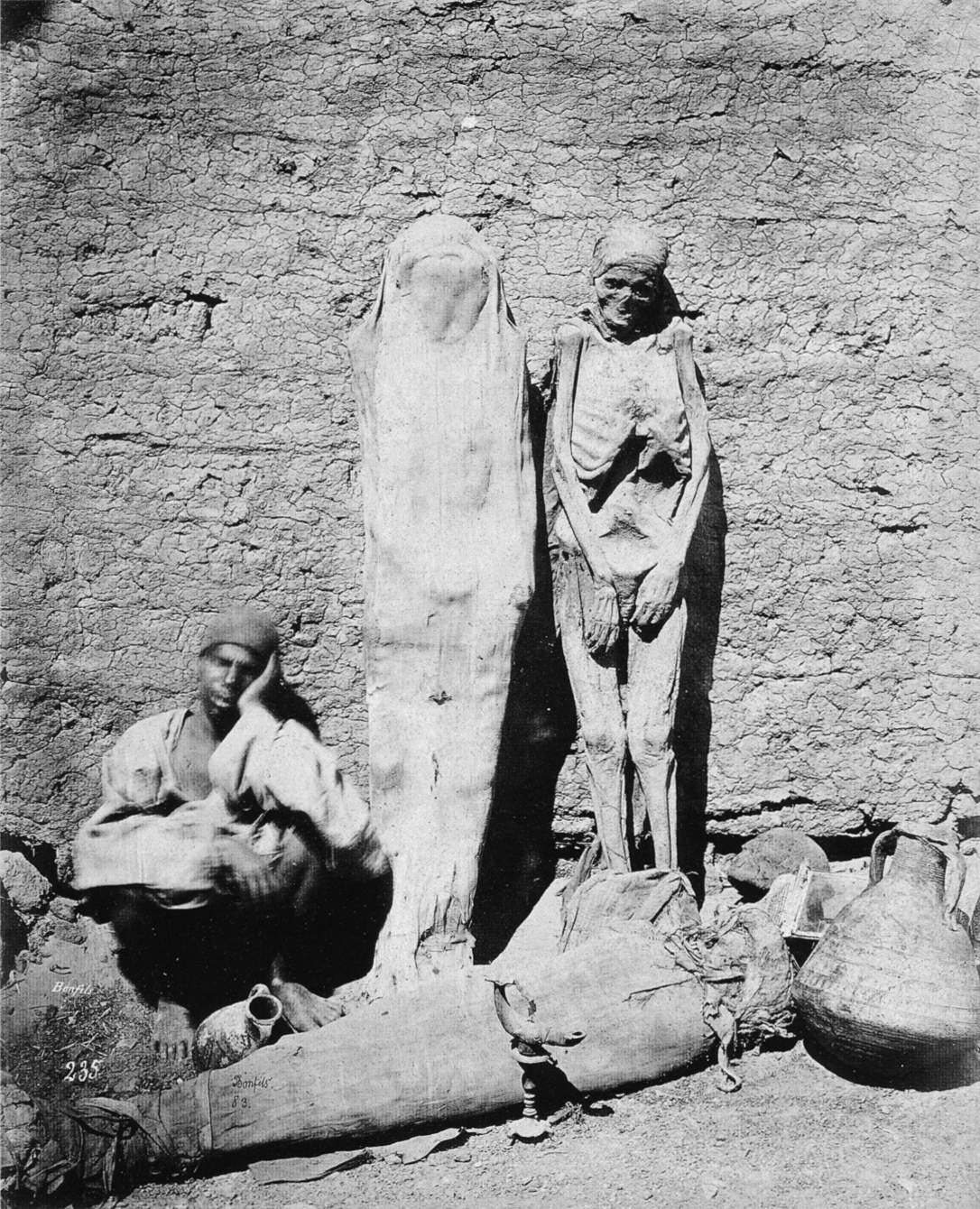 A 19th-century photograph by Félix Bonfils captures a mummy dealer dozing beside his wares, taken in Egypt around 1875
