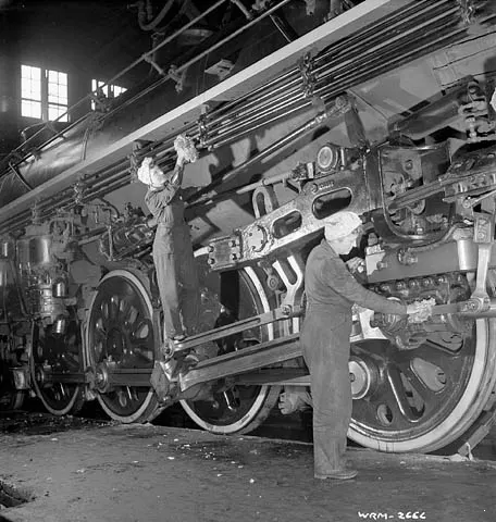 Two Canadian women clean a freight locomotive in 1943, part of the wartime shift that saw women take over industrial jobs traditionally held by men.