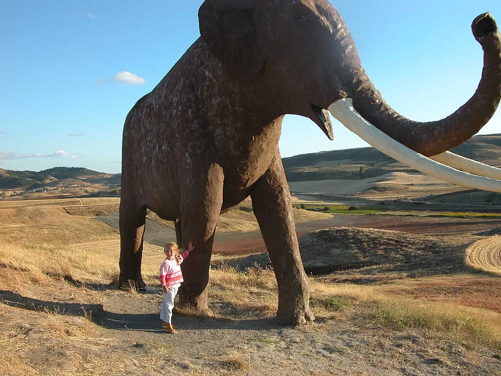 A fiber model of Palaeoloxodon antiquus stands at the archaeological site of Ambrona in Soria, Spain, a location listed as a Bien de Interés Cultural.
