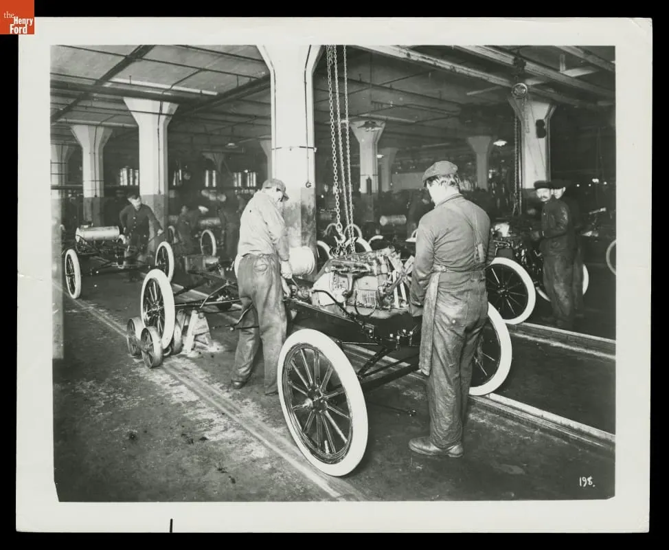 In 1913, workers at Ford’s Highland Park Plant installed engines on Model T chassis by hand. The assembly line was still static, with vehicles pushed from one station to the next.
