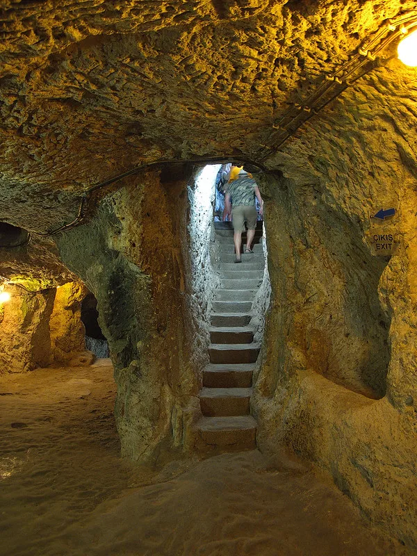 Inside Derinkuyu’s underground city in Turkey, a visitor climbs a narrow stairway once used by thousands seeking shelter from invasion.