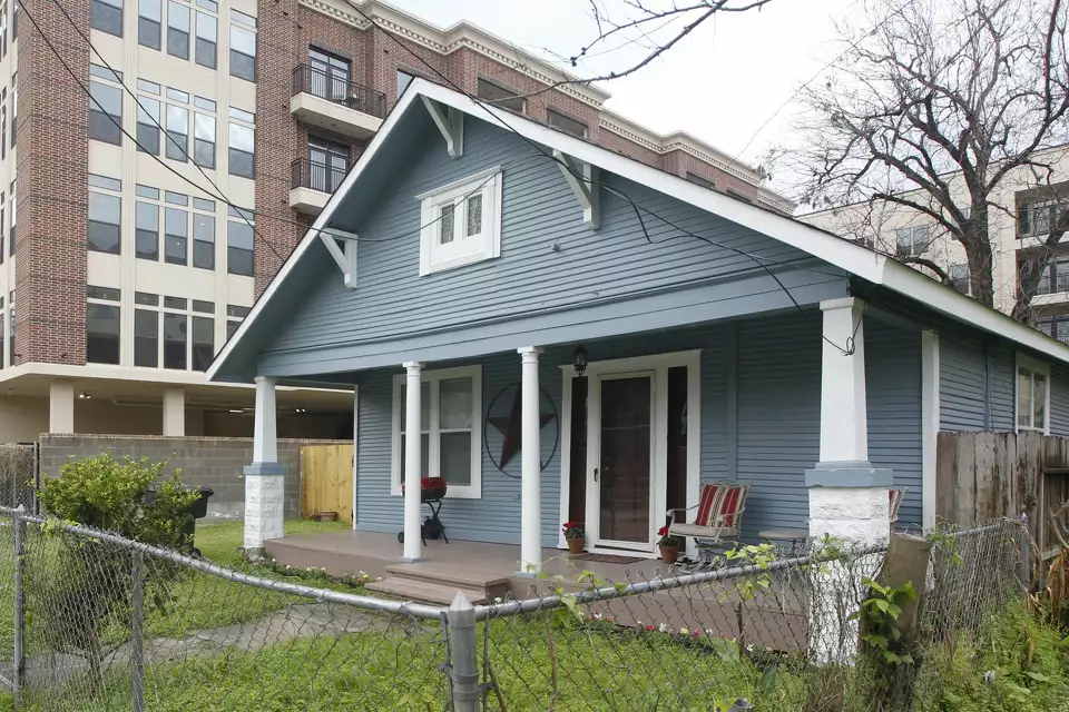 Mary Cerruti’s blue wooden bungalow at 610 Allston Street surrounded by modern apartment buildings in Houston Heights.