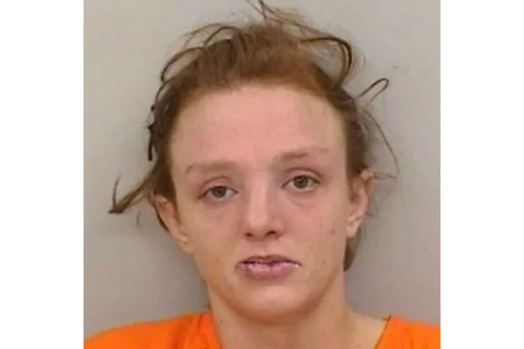 Booking photo of Kristin Bass wearing an orange jail uniform against a plain background.