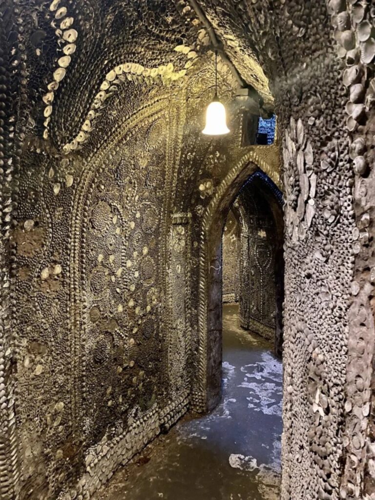 Narrow passageway inside the Margate Shell Grotto covered in intricate shell mosaics