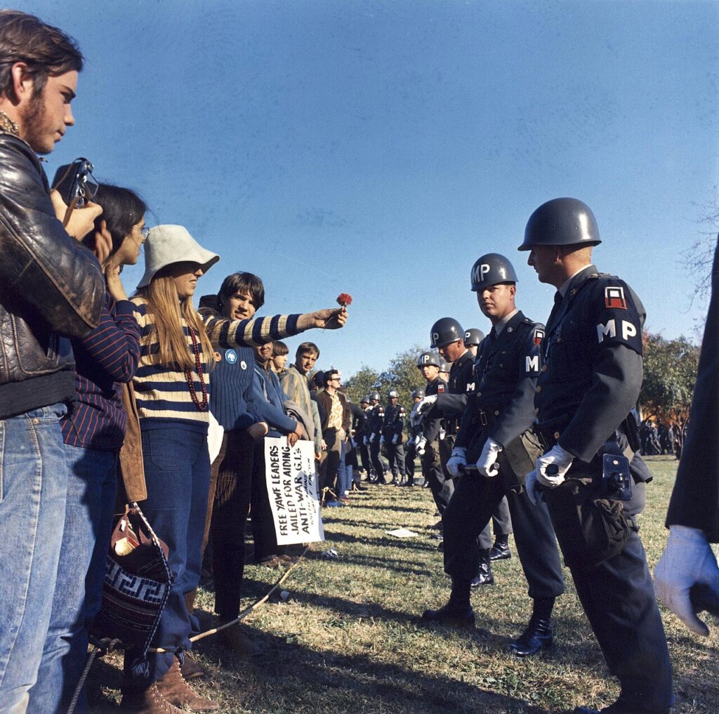 A female demonstrator offering a flower to military police on guard at the Pentagon during an anti-Vietnam demonstration in Arlington, Virginia.