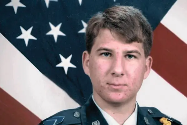 
Zebb Quinn in ROTC Uniform. It's a headshot where he is against the background of an American flag.