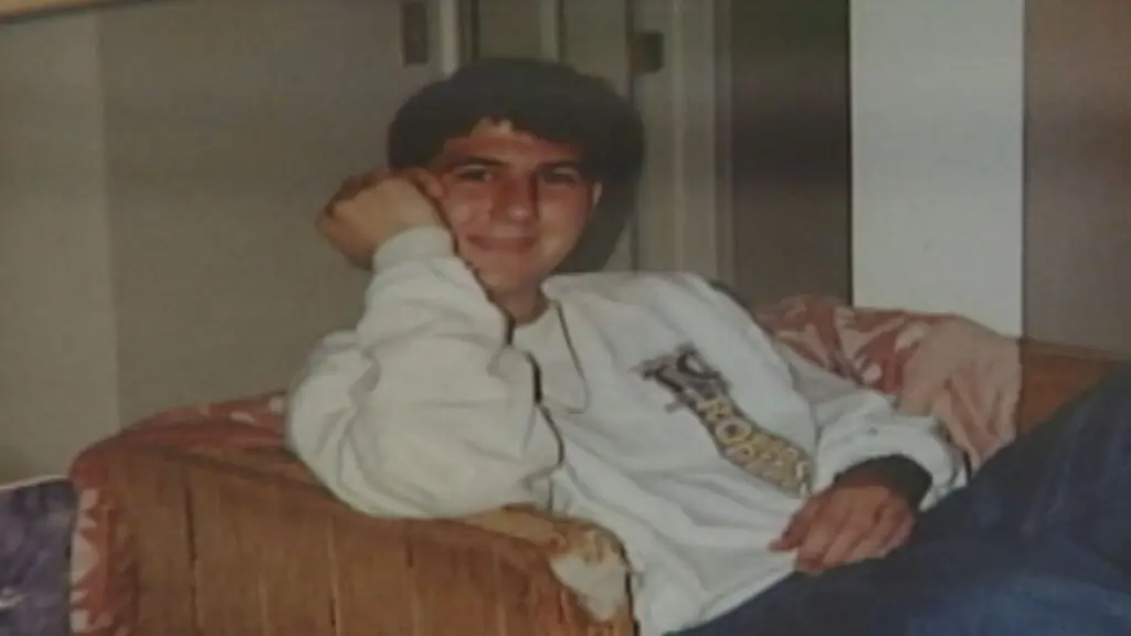 Zebb Quinn Sitting Happily. He is on a couch with one arm to his face.