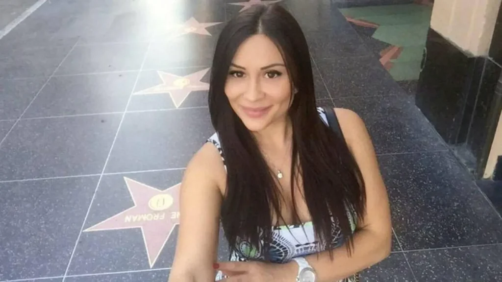 Iana Kasian takes a selfie on the Hollywood Walk of Fame in Los Angeles, smiling at the camera with the terrazzo stars visible beneath her. The image has been used in coverage of the 2016 West Hollywood murder case involving Kasian and Blake Leibel.