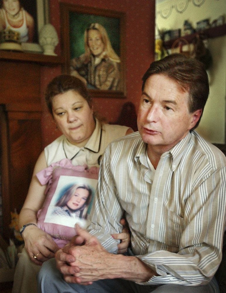 Magi and John Bish holding a pillow featuring a photo of their daughter Molly Bish.