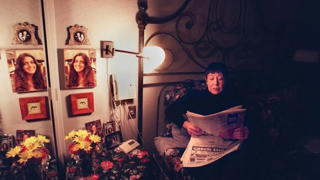 Susan Billig sitting in her bedroom surrounded by photographs of her missing daughter, Amy.