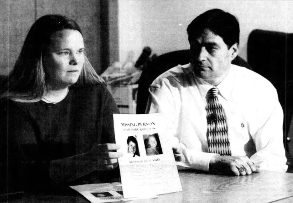 Kara Roberts holding a missing-person poster featuring her sister Leah Roberts.