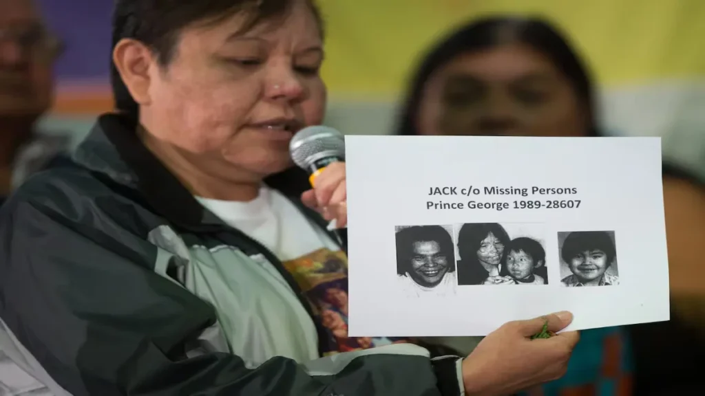Marlene Jack holding photographs of the four missing members of the Jack family.