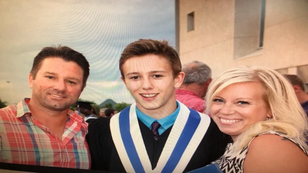 Ryan Shtuka posing with his parents, Scott and Heather Shtuka, during his high school graduation ceremony in Alberta.