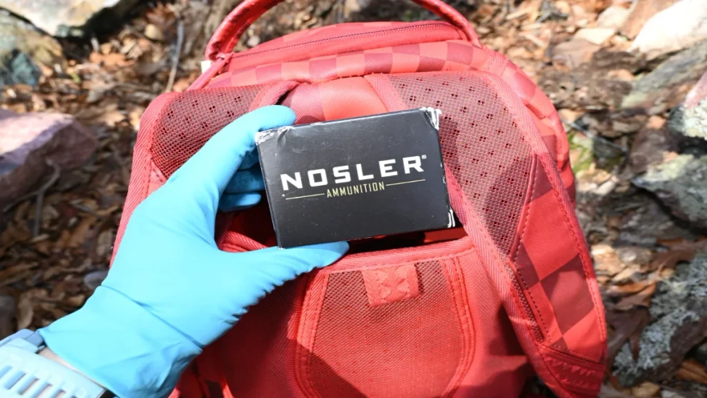 Investigator holding a box of ammunition recovered in the Qaadir and Naazir Lewis investigation.