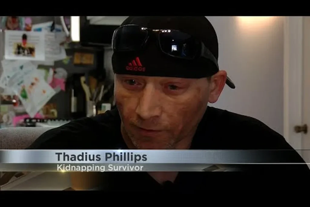 Thad Phillips, a kidnapping survivor, speaking during a televised interview, with an on-screen caption identifying him by name and as a “Kidnapping Survivor.”