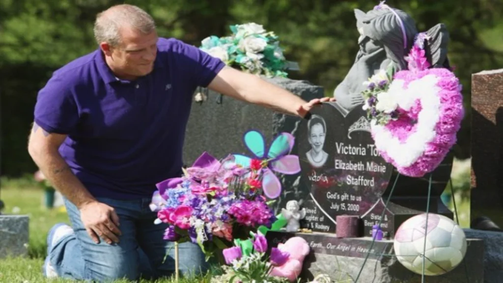 Rodney Stafford, the father of Victoria "Tori" Stafford, kneeling beside his daughter's grave site. 